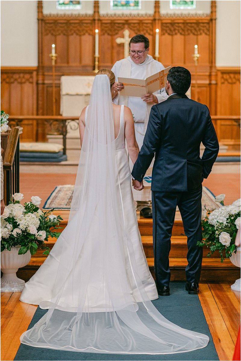 Bride and groom stand hand in hand in church for Maine Coastal Wedding