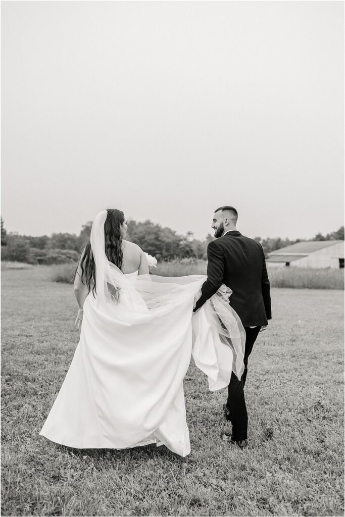 Groom holds bride's wedding gown for Summer Maine Wedding