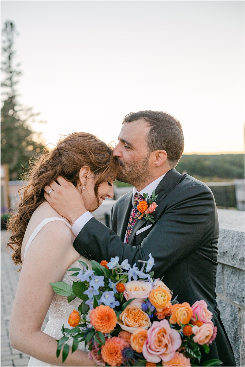 Groom kisses bride on forehead for Maine Fall Wedding