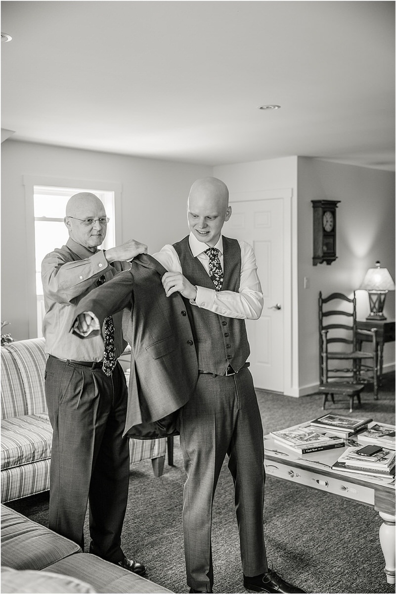Groom is helped into wedding attire for wedding at The 1812 Farm