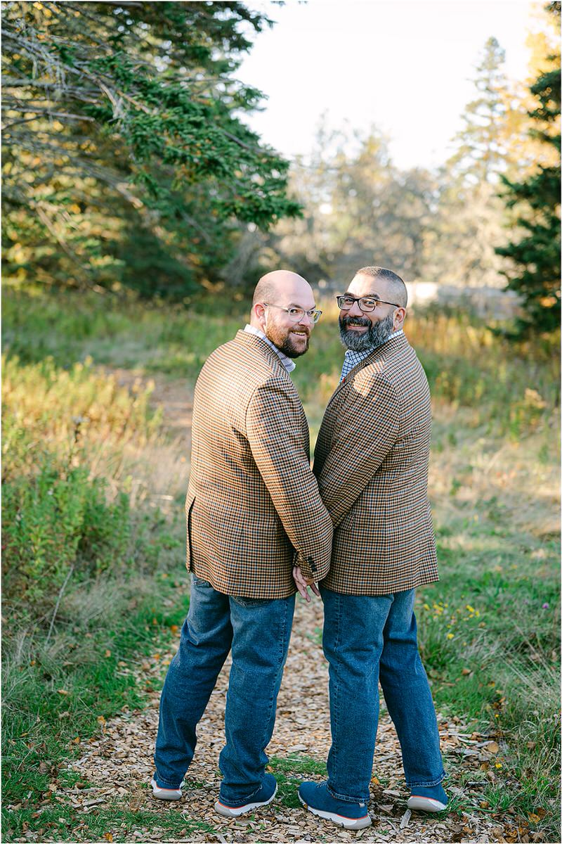 Two people look over their shoulders with a smile before their Maine fall elopement