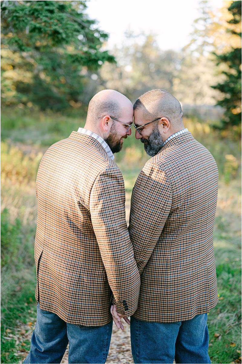 Two men bring their heads together before their Maine fall elopement