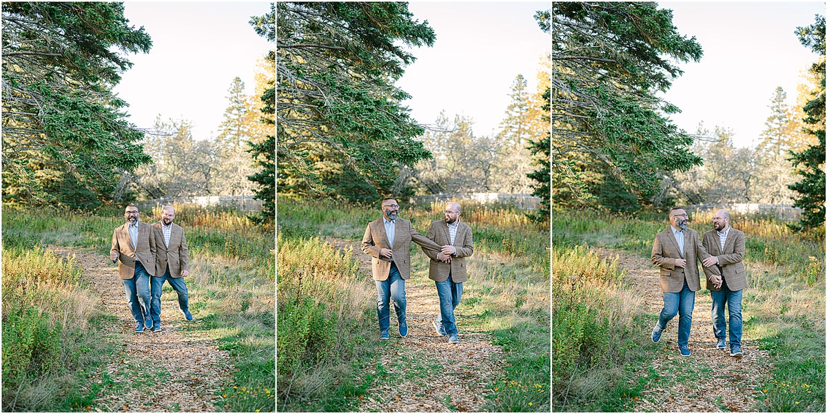 Couple happily walk together threw the woods before their Maine fall elopement
