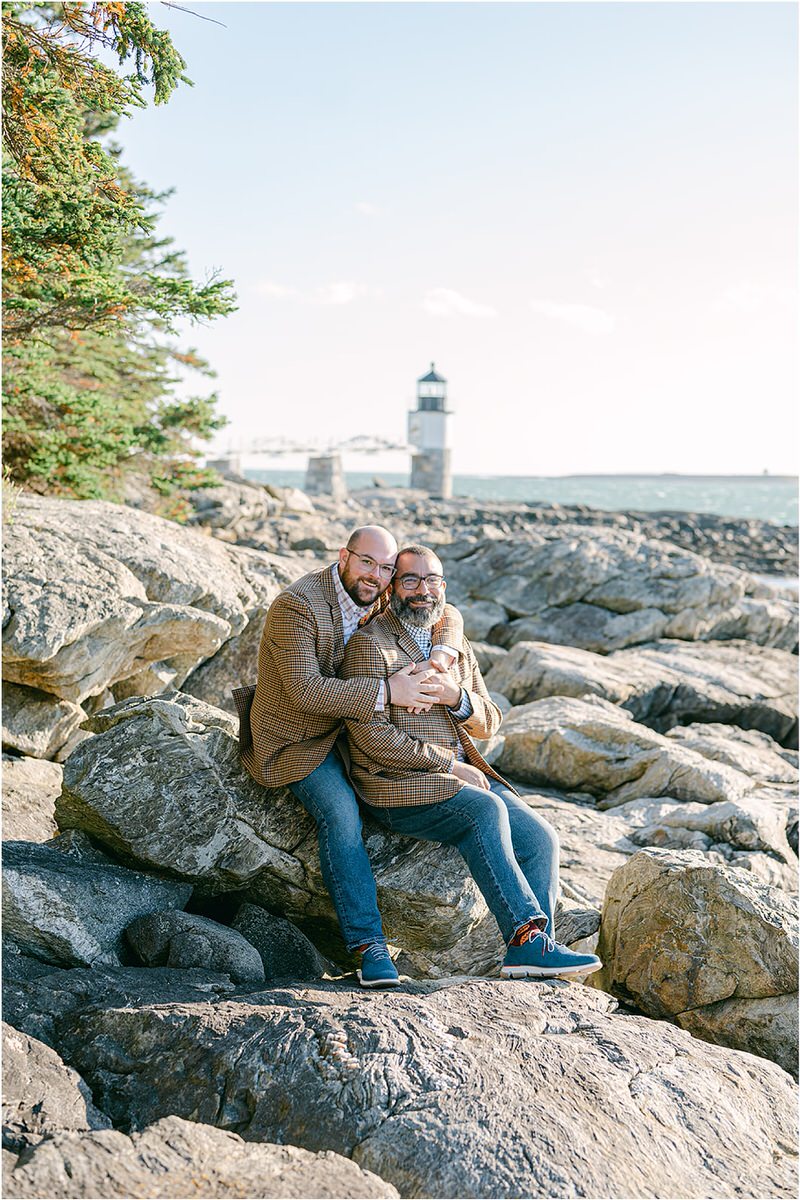 Two people sit on the rocks together before their Maine fall elopement