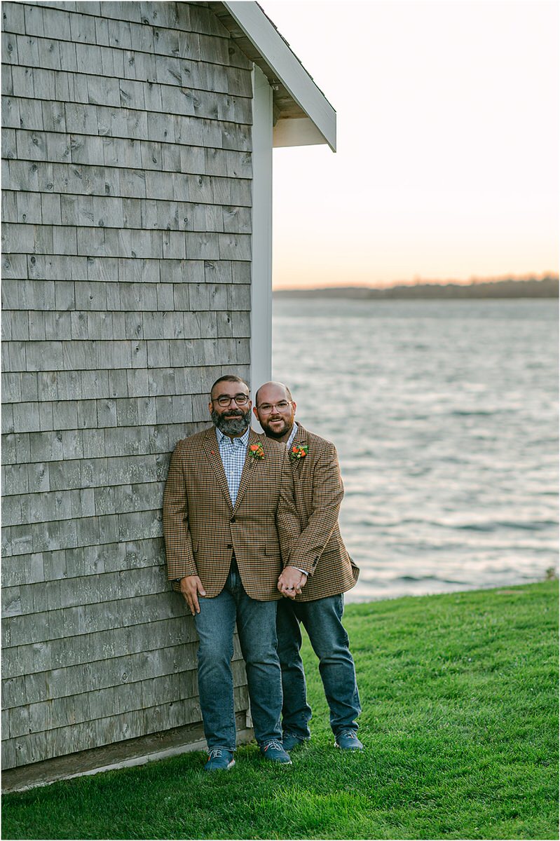 Two guys stand together near a lighthouse before their Maine fall elopement