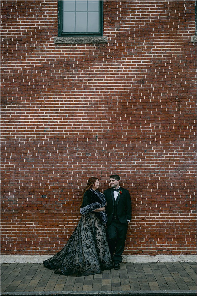 Couple stand together in front of a brick wall for Rachel Campbell Photography