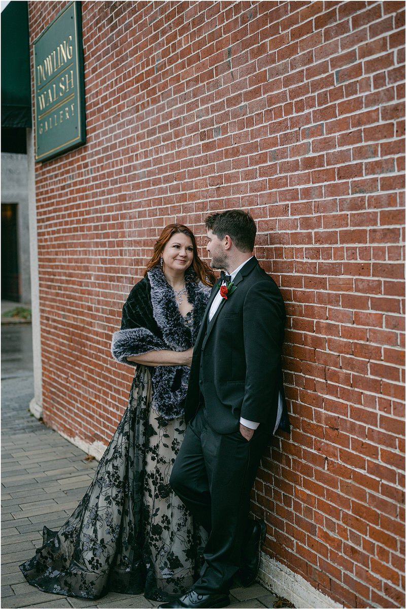 Man and woman stand together in front of a brick wall for Rachel Campbell Photography