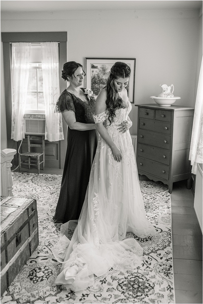Bride is getting into wedding gown by Rachel Campbell Photography