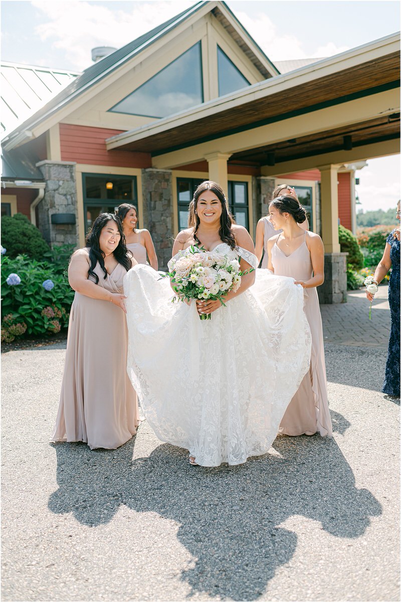 Bridesmaids help bride with her dress at The Red Barn at Outlook Farm